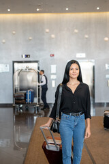 Poster - Happy young woman with suitcase moving down hotel lobby