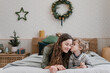 © Alina Hvostikova/Stocksy - Boy kissing mother on bed on Christmas eve