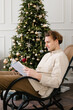 © Alina Hvostikova/Stocksy - Young man reading book on rocking chair during Xmas holidays