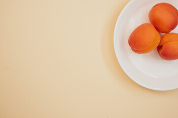 Canvas Print - Top view of fresh three apricots on a plate isolated on light brown background