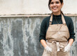 © Malquerida Studio/Stocksy - Portrait of a young ceramist woman with  hands dirty of clay in front of a wall