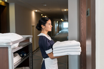 Poster - Young chambermaid bringing clean sheets to one of hotel clients