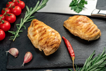 two grilled chicken breasts on a stone background