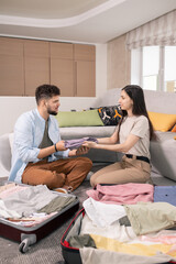 Poster - Happy couple packing clothes into suitcases while going for journey
