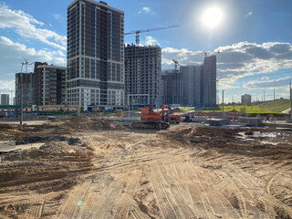 Wall Mural - A large construction site of new tall large houses of concrete monolithic-frame buildings with cranes and construction equipment during the repair of new buildings in a large densely populated city