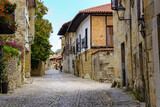 Fototapeta Uliczki - Narrow street with old stone houses and cobblestone pavement. Santillana del Mar.