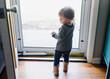 © Maria Manco/Stocksy - Back view of toddler girl looking out front screen door