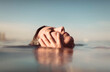 © Ibai Acevedo/Stocksy - Girl holding her head with her hands at the beach