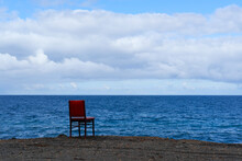 Lonely Chair On The Coast With The Blue Sea In The Background.