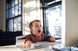 © Anna Tabakova/Stocksy - Little boy looking surprised while using desktop compute and a mouse