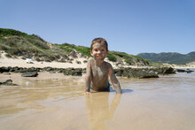 Child With The Body Slathered In Mud On A Beach
