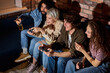 © alfa27 - Diverse Students enjoying of playing in video game, rest at home. Smiling surprised excited american people have fun with joysticks in living room interior, free space