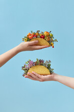 Women Holding Tacos With Flowers On Blue Background