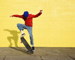 © Angela Waye/Stocksy - Cool Boy Skating Outside with Yellow Wall