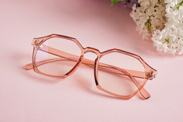 Wall Mural - trendy eye glasses and a branch of white lilac on a pink background, eye glasses and flowers