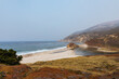 © Simone Anne/Stocksy - Ocean and cliffs with a deserted beach on a half foggy day