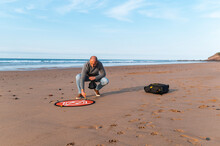 Man Preparing Landing Pad For Flying Drone  On Beach 