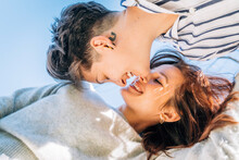 Smiling Lesbian Women About To Kiss Against Blue Sky