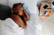 © Jimena Roquero/Stocksy - Woman sleeping in bed with head wrap from above