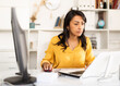 © JackF - Smiling Latin American businesswoman sitting in office at workplace and looking at camera