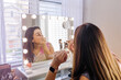 © ByLorena/Stocksy - Charming woman doing makeup in front of mirror