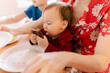 © Léa Jones/Stocksy - Baby on mother's lap eating a sausage