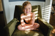 © Jakob Lagerstedt/Stocksy - Cute young boy sitting a chair with light and shadow falling on him