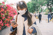 © Pansfun Images/Stocksy - Young woman with mask use mobile phones in the street