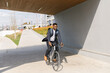 © Mihajlo Ckovric/Stocksy - Young african american businessman riding a bicycle to work in the urban city zone