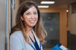 © VICTOR TORRES/Stocksy - Happy real medic woman holding a folder while standing in hospital corridor
