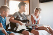 © Albert Martinez/Stocksy - Siblings learning to play the electric guitar, home schoolingtogether