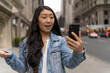 © blvdone - Young Asian woman in city walking face time video chatting