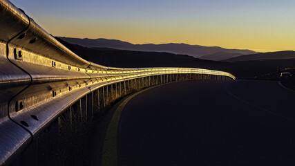 Wall Mural - Closeup of the metal traffic barrier on the side of the road, hills on a beautiful evening