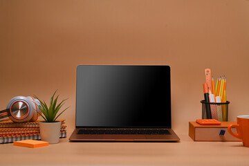 Front view laptop and equipment orange background.