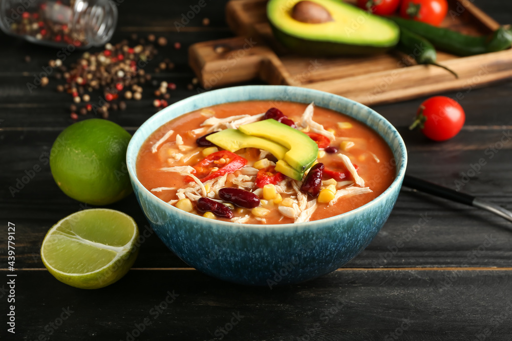 Bowl of tasty chicken enchilada soup on table