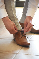 Sticker - Unrecognizable groom tying the shoelaces of brown classic leather shoes