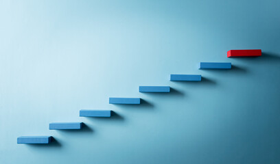 Concept of building success foundation. Yellow and red wooden block stacking as step stair, Success in business growth concept on pastel blue background.