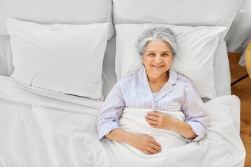 Poster - sleeping, old age and people concept - happy smiling awake senior woman lying in bed at home bedroom