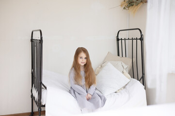 Wall Mural - little red haired girl sitting in a country house on a bed, summer vibes concept