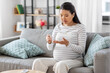 © Syda Productions - pregnancy, health and glycemia concept - pregnant asian woman checking blood sugar level with glucometer and lancing device at home