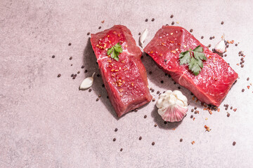 Raw beef steaks on a grey stone background