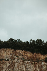 Sticker - Vertical shot of trees in a rocky landscape on a cloudy day