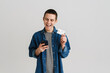 © Drobot Dean - Young white man using cellphone while posing with credit card