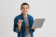 © Drobot Dean - Young man smiling while holding credit card and laptop
