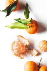 Wall Mural - Oranges fruits composition with green leaves and slice on white wooden background, top view