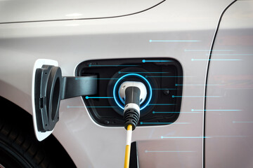 EV Car or Electric car at charging station with the power cable supply plugged in with Blue lights background. Eco-friendly alternative energy concept