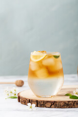 Wall Mural - Vertical shot of a cold refreshing glass of lemonade with ice cubes on a wooden board