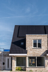 Newly build houses with solar panels attached on the roof against a sunny sky Close up of new building with black solar panels. Zonnepanelen, Zonne energie, Translation: Solar panel, , Sun Energy