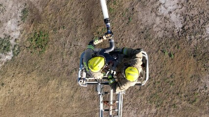 Poster - Firefighters on stairs extinguish a big fire. View from drone.