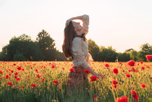 Young woman dancing on the poppy field